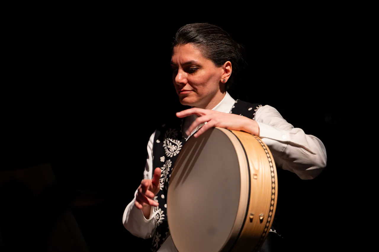 Sara Fotros playing a frame drum during a performance.